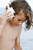 Boy holding sea shell to his ear