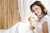 Young woman drinking tea in bed