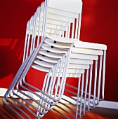 Stacked white chairs against red background