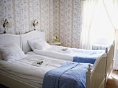 Romantisches Schlafzimmer mit weißem Doppelbett und Blümchentapete