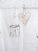 Two wind chimes (one heart-shaped) hanging on a white wall