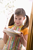 Girl in apron holding plates and cutlery