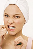Close-up of a young woman flossing her teeth