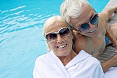 Älteres Paar auf Holzliege am Swimmingpool