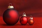 Three Christmas baubles in shades of red