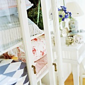 Vitrinenschrank mit verschieden gemusterten Kissen in skandinavischem Schlafzimmer