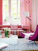Wohnzimmer mit Couch in rosa Tönen vor dem Fenster; Designer-Sessel und Couchtisch