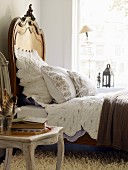 Bett mit geschwungenem Holz Kopfteil und Spitzen Bettwäsche in romantischem Stil, Stuhl mit gebogenem Gestell auf Flokati Teppich