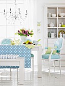 A blue and white dining room with upholstered chairs and a wooden bench with a crockery cupboard in the background