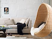Ecru couch with scatter cushions and comfortable, wicker hanging chair with fur blanket