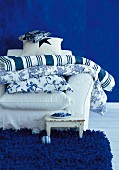Cushions on white armchair against blue wall