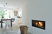 Basket in front of fireplace in open-plan interior with white walls