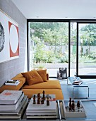 Ockerfarbenes Sofa in Wohnzimmer eines modernen Stadthauses mit raumhohen Glasschiebetüren zum Garten