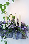 White candles in zinc-plated flower pots of campanula and petunias