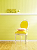 Wand mit grüner Tapete und Stuckleiste als Ablagefläche, davor Stuhl mit Kissen