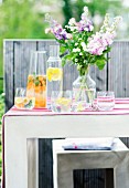 Mit Früchten aromatisiertes Wasser & Blumenstrauss auf Tisch im Freien