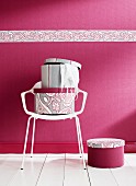 Hatboxes on white chair against deep pink wall