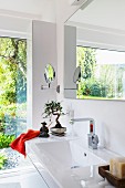 Helles Badezimmer mit Fensterfront, Waschtisch mit breiter Ablage & astiatischen Dekoobjekten