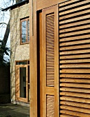 Louvered shutters made of light wood on the facade of a home