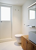 Badezimmerecke mit Waschschüssel auf Unterschrank aus Holz neben WC