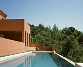 Vacation mood - by the pool in front of a Mediterranean home with a reddish brown facade