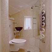 Bathroom tiled with light colored tiles and WC beside a vanity with a wood wash basin across from a shower stall