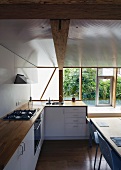 Kitchen counter with wood work surface in front of a modern bank of windows