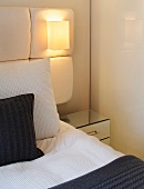 Detail of bed with upholstered head and integrated wall lamp
