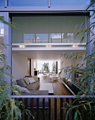 View through open balcony doors into a living room with a sofa in designer style