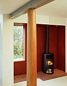 Wood burning stove in front of a red wall and wooden columns in a lobby