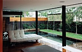 White leather sofa in front of a terrace window and a view of a pool in a city garden