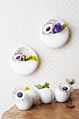 Goldenrod, blue daisies and lisianthus in round vases on a table and on a wall