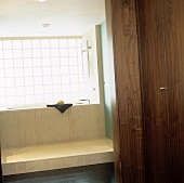 A view through an open door onto a bath tub and a light wooden pedestal