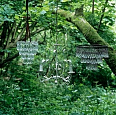 Crystal chandeliers hanging from a tree in a wild garden