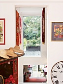 Hat collection on Chinese dresser next to wall opening with view of terrace