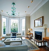 Traditional living room with bay window, green glass chandelier above sofas and fireplace