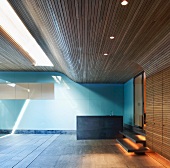 Modern room with wood cladding on ceiling and wall and covered swimming pool