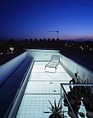 Roof terrace lit by transparent floor under an evening sky in the city