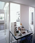 Desk with architecture models in front of ceiling-height windows with view of stairwell