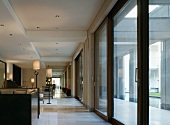 Various seating areas and standard lamps along a row of windows with large sliding doors