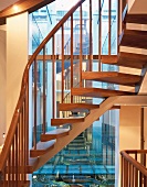 Open apartment stairs with wooden treads and metal supports in front of reflective window