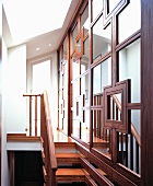 Mirrored wall with elaborate framing beside narrow wooden stairs and an open hall