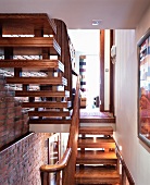 Two flights of wooden stairs next to brick wall with view of open-plan, traditional living room