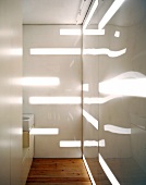 Bathroom with illuminated bands and reflections on white painted glass wall
