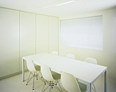 Purist room with white table and Bauhaus chairs in front of fitted cupboards