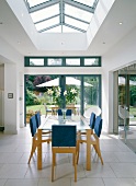 Chairs with cushioned backs and blue covers in front of terrace window in modern house