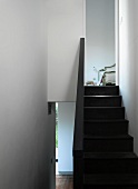 Dark wood stairs and balustrade in white modern stairwell