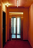 Traditional corridor in yellow shades with modern glass lift