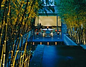 Terrace with pool at dusk with illuminated stands of bamboo