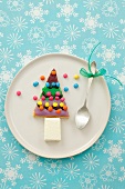 A Christmas tree shaped biscuit with ice cream and colourful chocolate beans